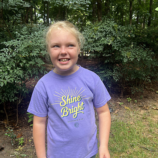 Child wearing the Shine Bright youth tee in Violet